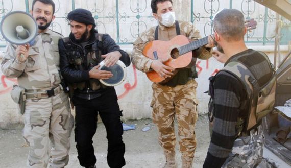 Members of the Free Syrian Army chant as one of them plays the guitar near Nairab military airport in Aleppo