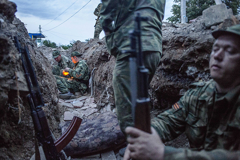 Des soldats séparatistes dans une des tranchées du check point de Semenivka. La nuit commence à tomber alors que deux pro russes s'allument une cigarette. Semenivka. Ukraine. 19/05/2014